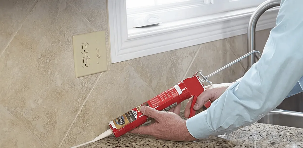 Handyman applying caulk along a kitchen backsplash and countertop seam in Bradenton, FL